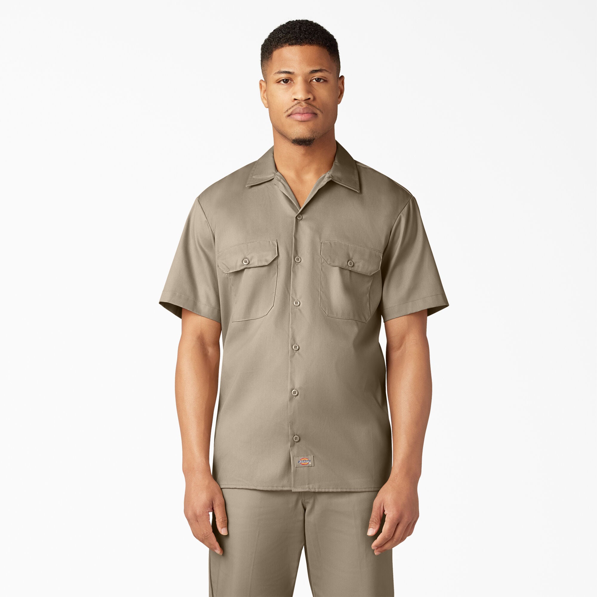 Man wearing a dickies dark sand short-sleeve shirt and dark sand dickies pants on a white background